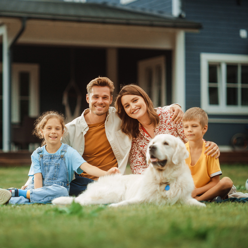 Happy family with a kids and a white Golden retriever dog sitting on a grass