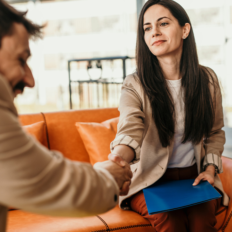 Man and woman handshaking while collaborating on realtor business