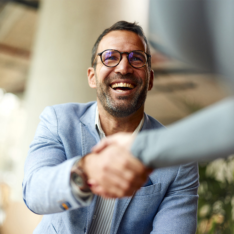 Happy male entrepreneur greeting his colleague while working in the office